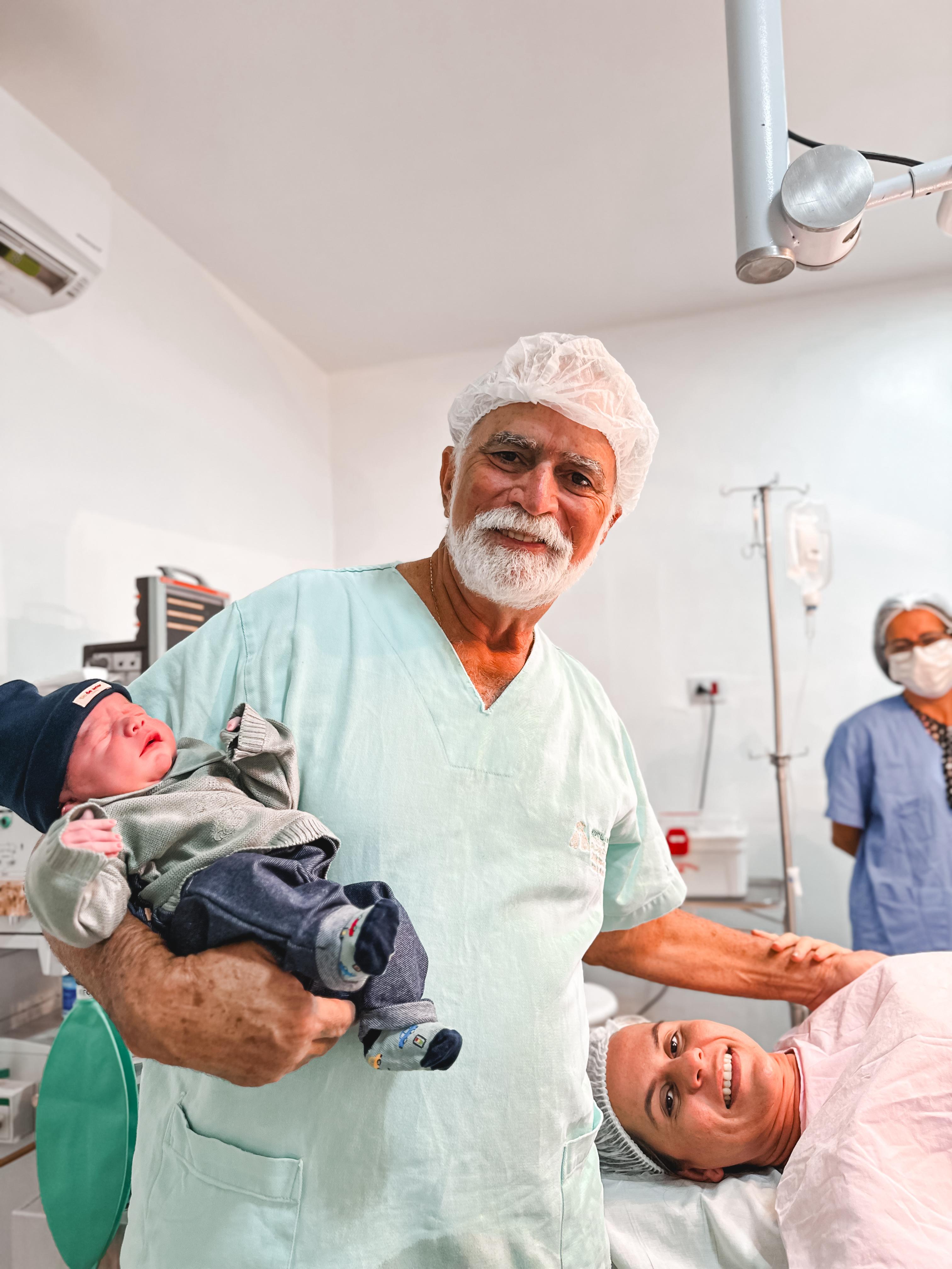 Foto do medico segurando um recem nascido